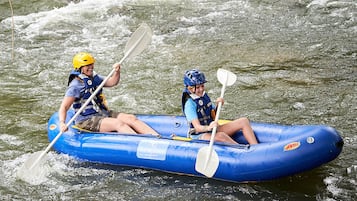 Deux personnes se trouvent dans un radeau gonflable bleu sur une rivière.