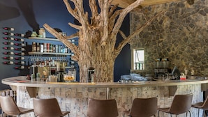 Un bar doté d’une structure centrale en forme d’arbre, de tabourets et d’étagères remplies de bouteilles.