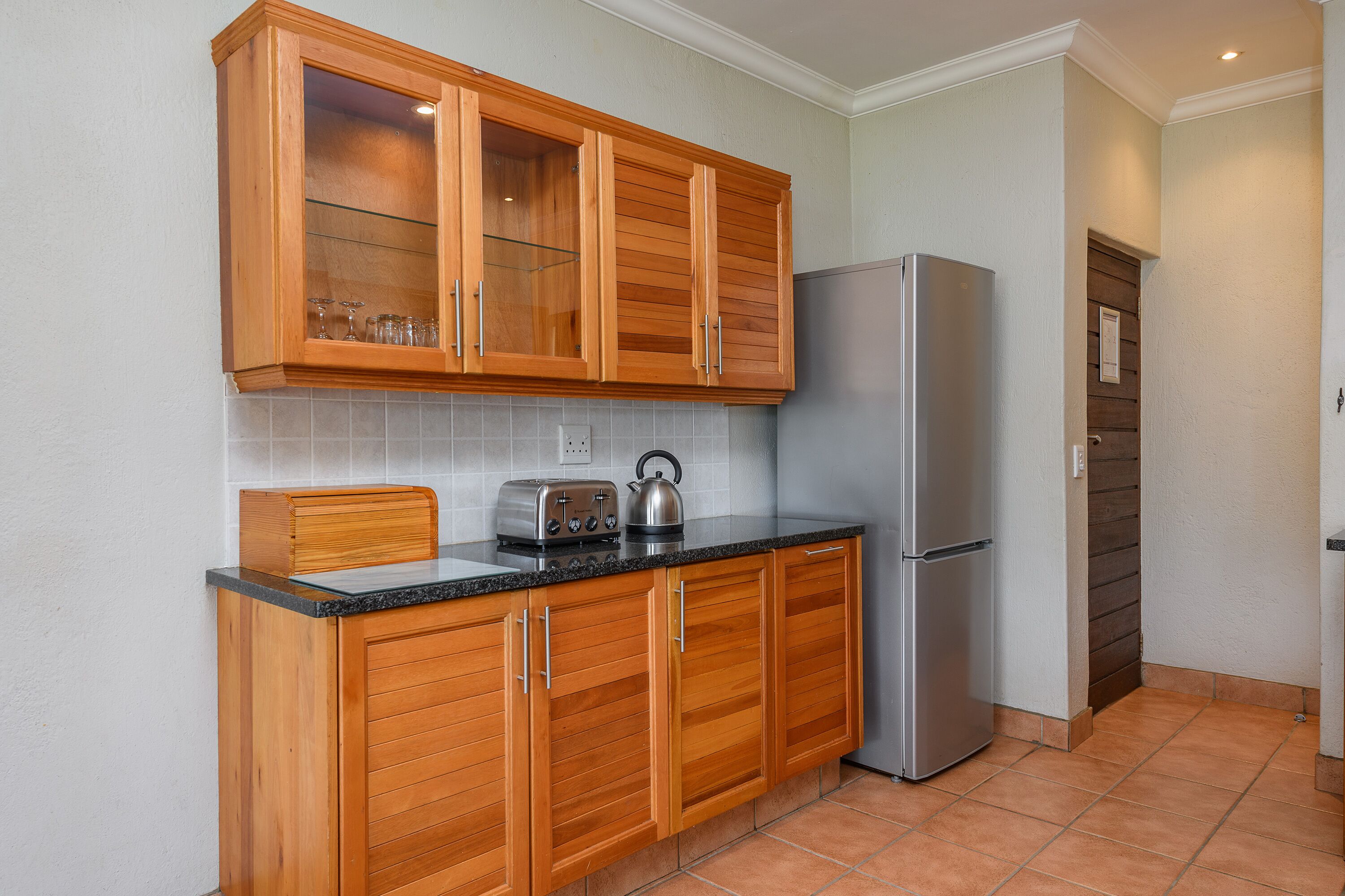 Una cocina con armarios de madera, un refrigerador de acero inoxidable y un tostador en la encimera.