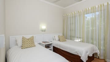 A hotel room with two beds, a nightstand, a ceiling fan, and a window with curtains.