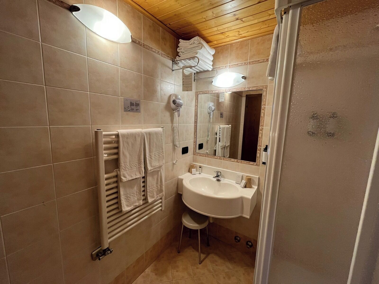 Een badkamer met een wastafel, spiegel, handdoekhouder en een haardroger.