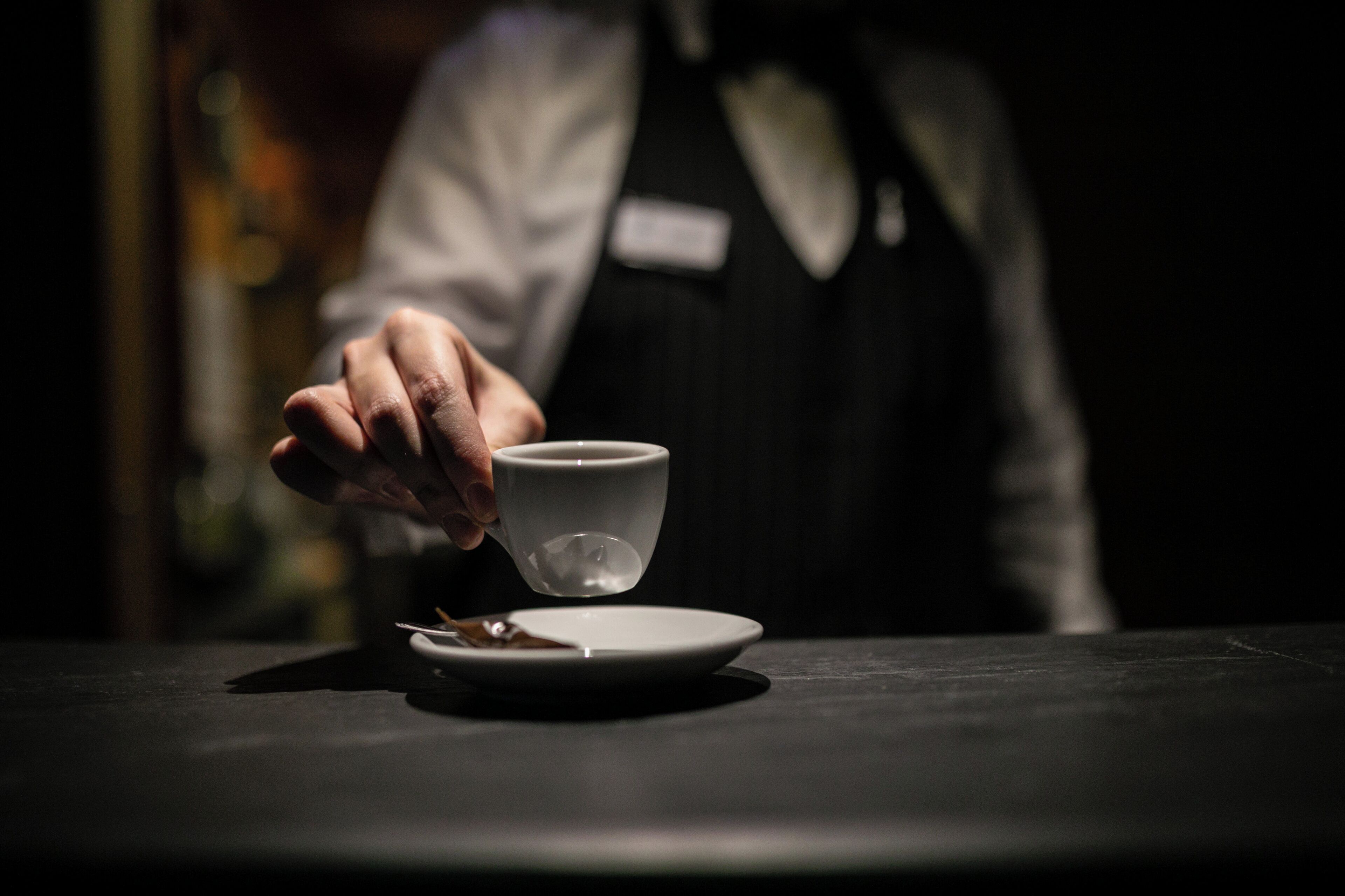 Une personne servant une tasse de café sur une table.