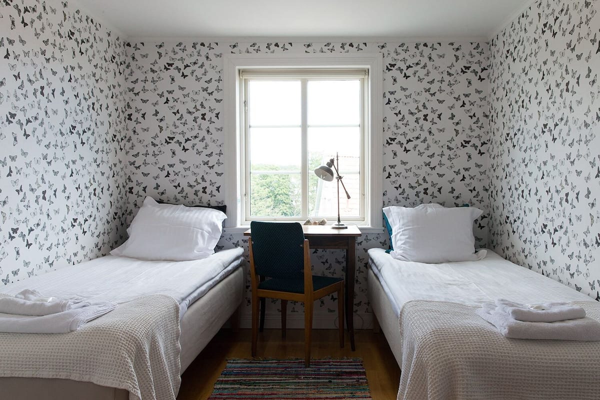 Chambre avec lits jumeaux, salle de bains commune | Décoration personnalisée, bureau, fer et planche à repasser