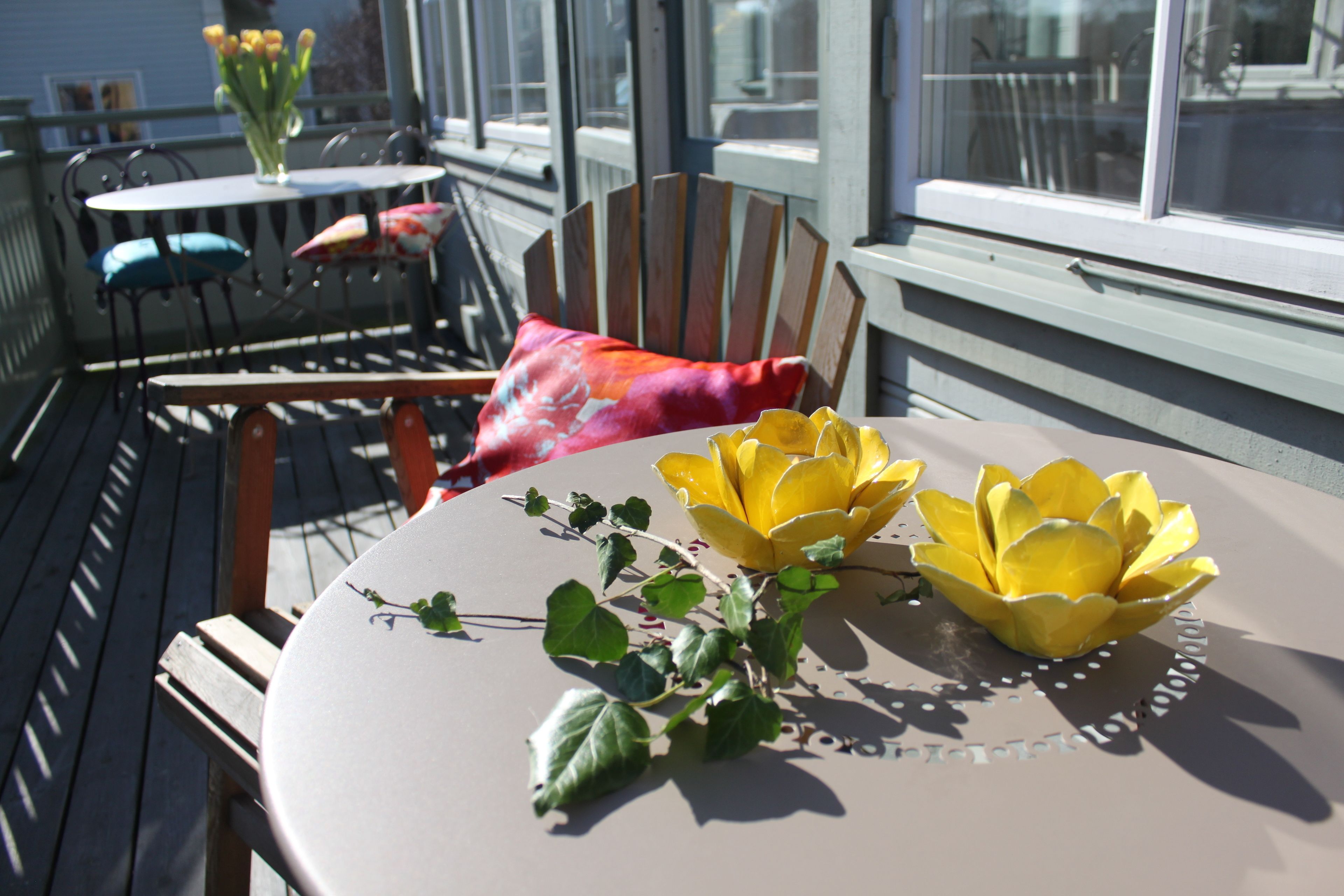 A round table with a yellow lotus centerpiece, a chair with a colorful cushion, and a small plant with green leaves.