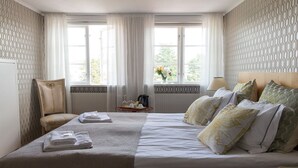 Habitación de hotel con una cama grande, una silla, una mesa con bandeja y una ventana con cortinas.