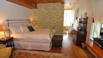 Een slaapkamer met een bed, nachtkastje, lamp en een stenen muur.
