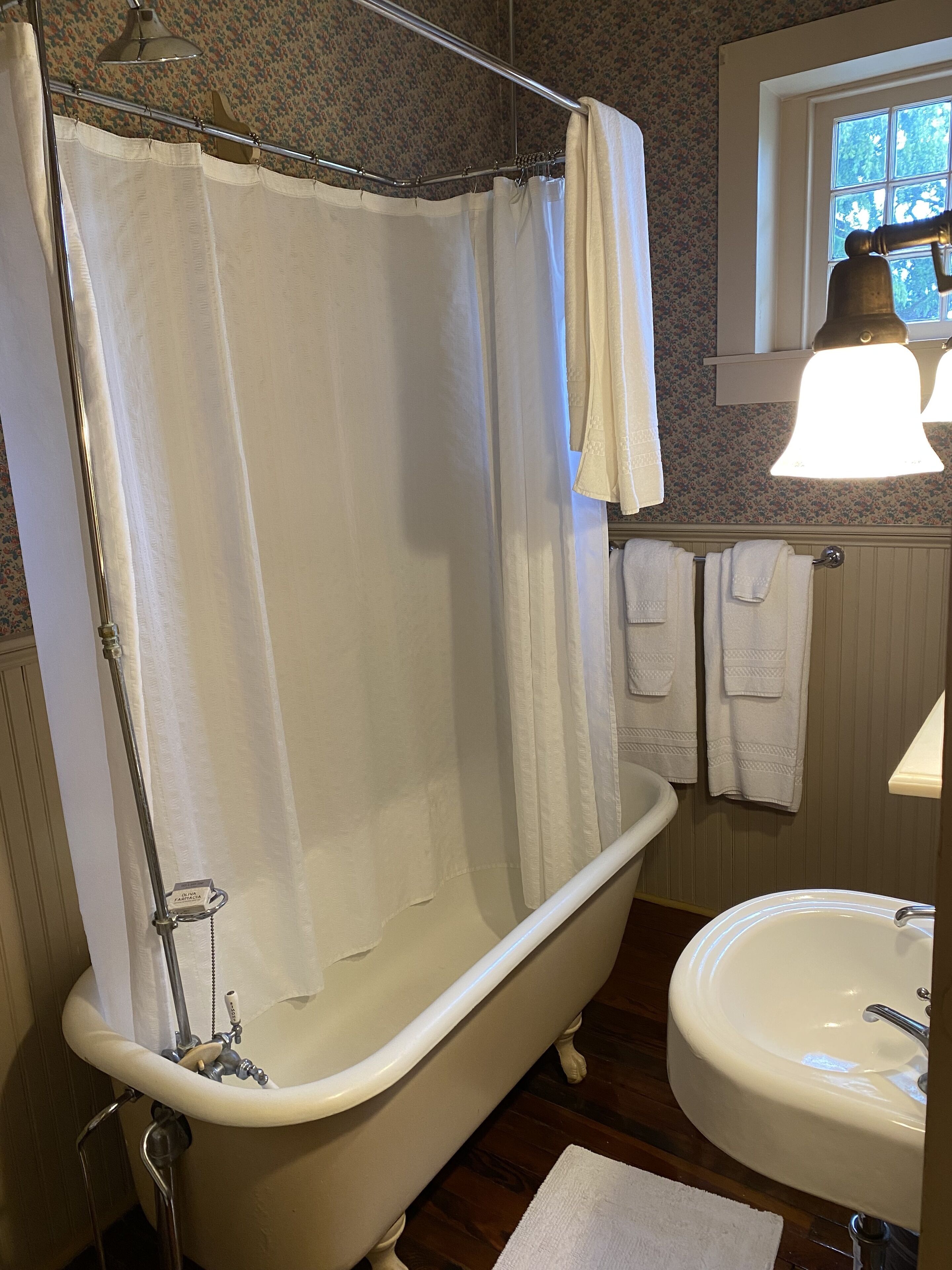 A bathroom with a clawfoot bathtub, a white sink, and a shower curtain.