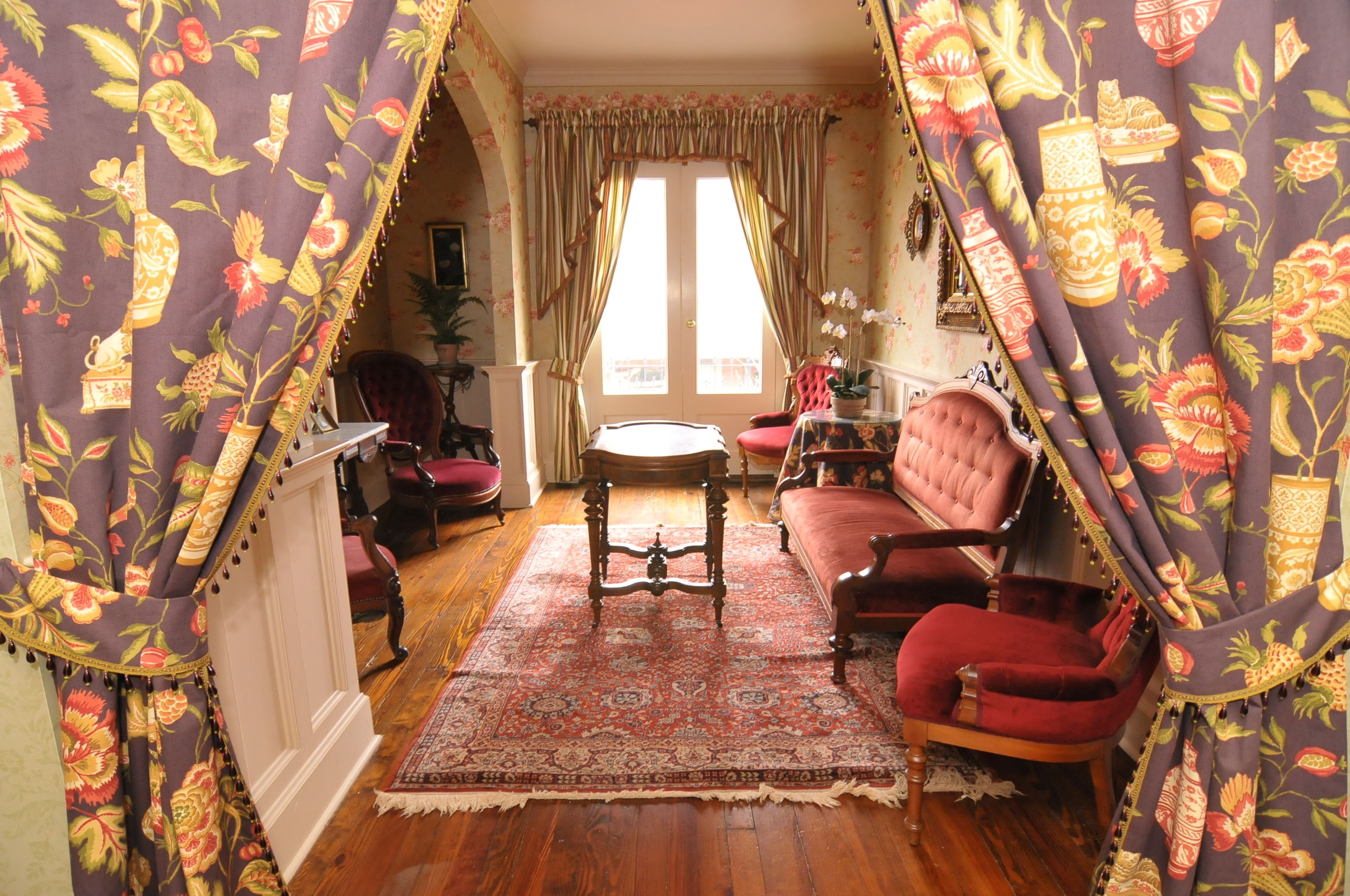 Une pièce au décor traditionnel, avec un canapé en velours rouge, une table basse en bois et un tapis à motifs.