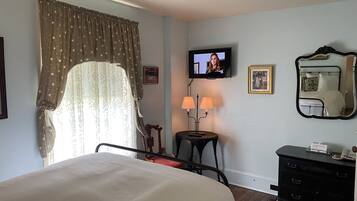 A hotel room with a bed, a television, a dresser, a mirror, and a table with two lamps.