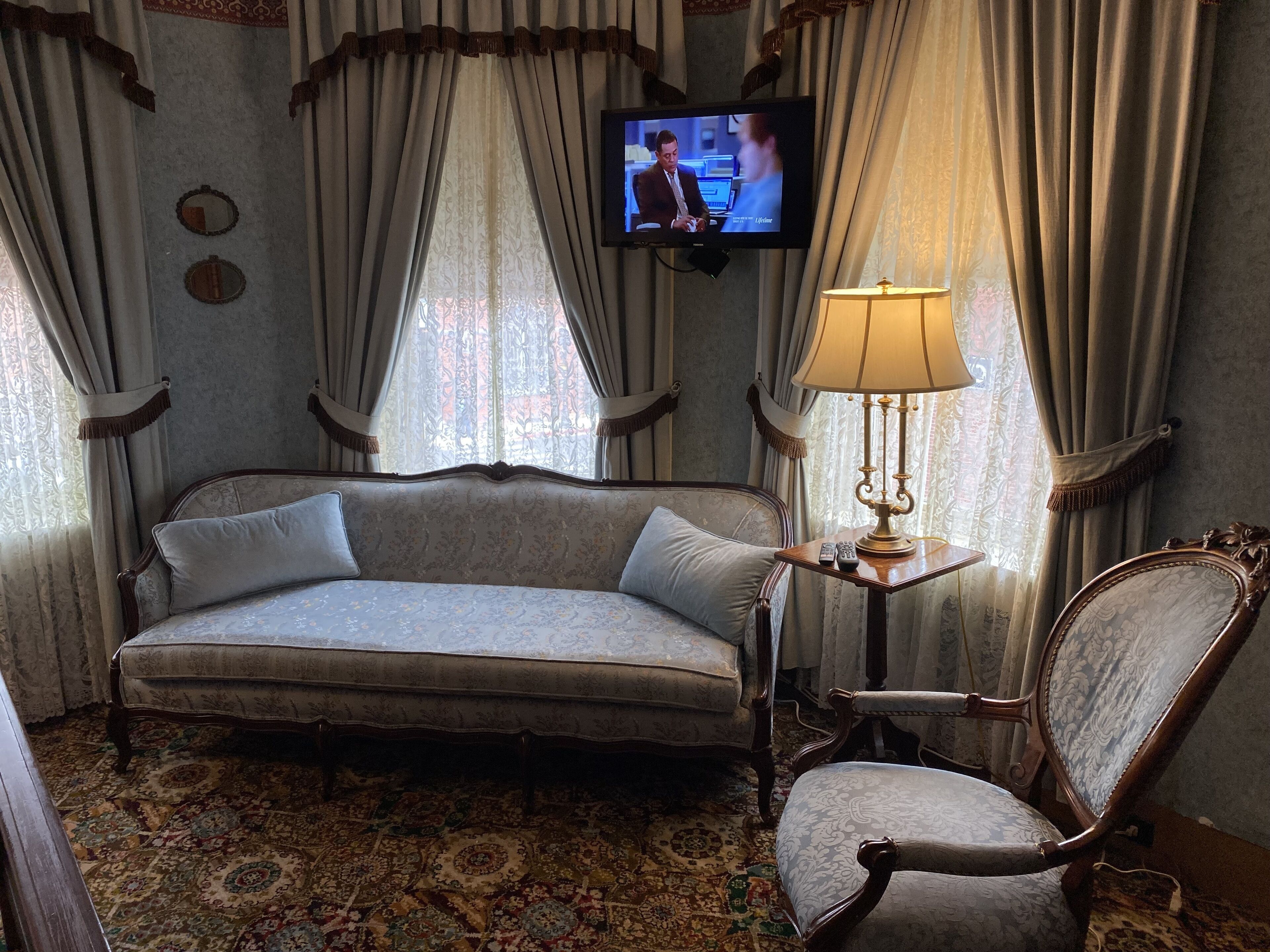 A room with a sofa, a chair, a television, and a lamp.