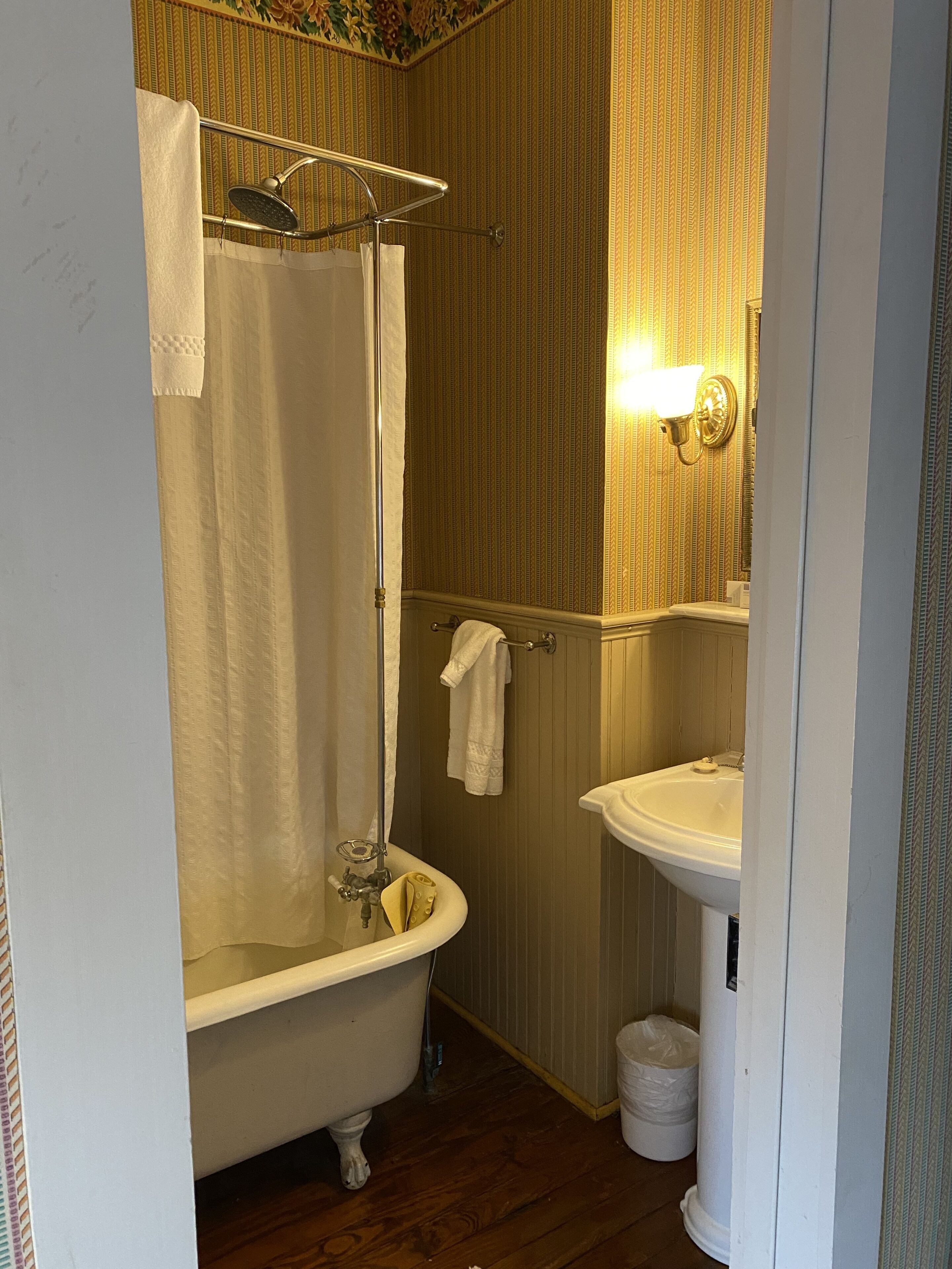 A bathroom with a clawfoot bathtub, a sink, and a shower curtain.