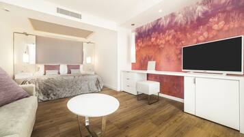 Habitación de hotel moderna con una cama grande, un escritorio blanco, un televisor de pantalla plana y un llamativo mural floral.