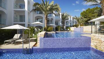 A pool area with tiled steps, lounge chairs, and umbrellas.