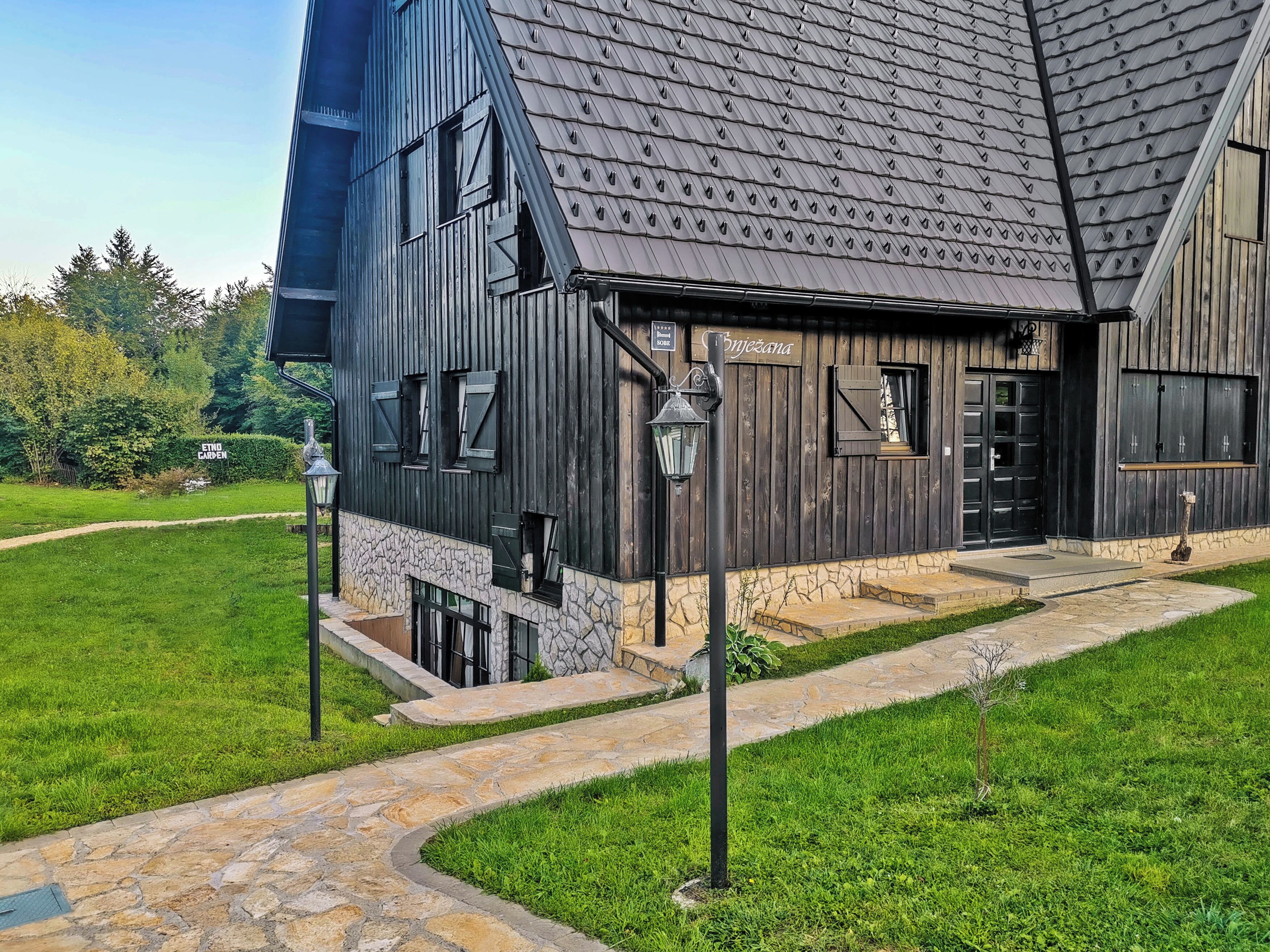 Ein rustikales Gebäude mit geneigtem Dach, steinernen Fundament und einem Weg zum Eingang.