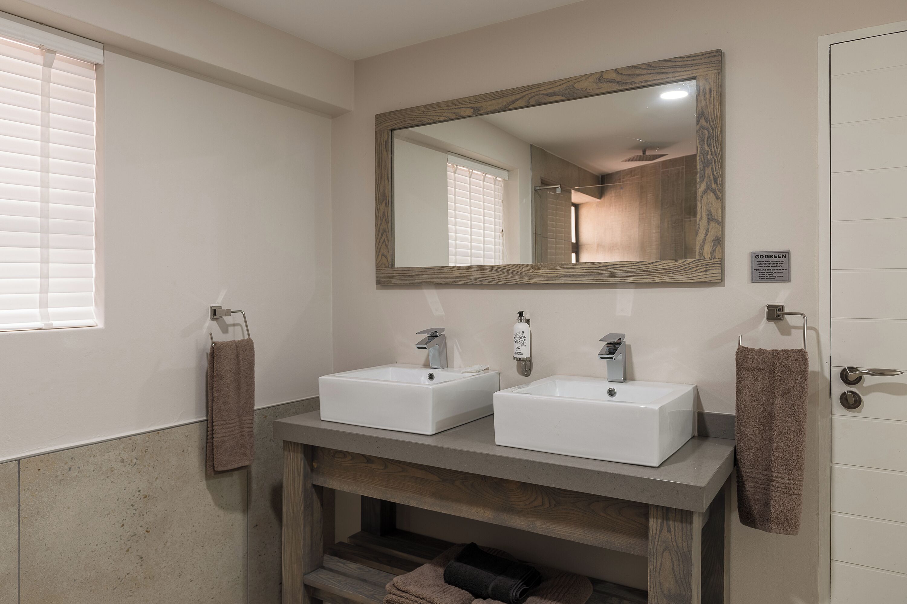 A bathroom with two sinks, a mirror, and a towel rack.