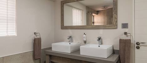 A bathroom with two sinks, a mirror, and a towel rack.