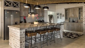 Una cocina moderna con una isla central, taburetes de bar y un refrigerador de acero inoxidable.