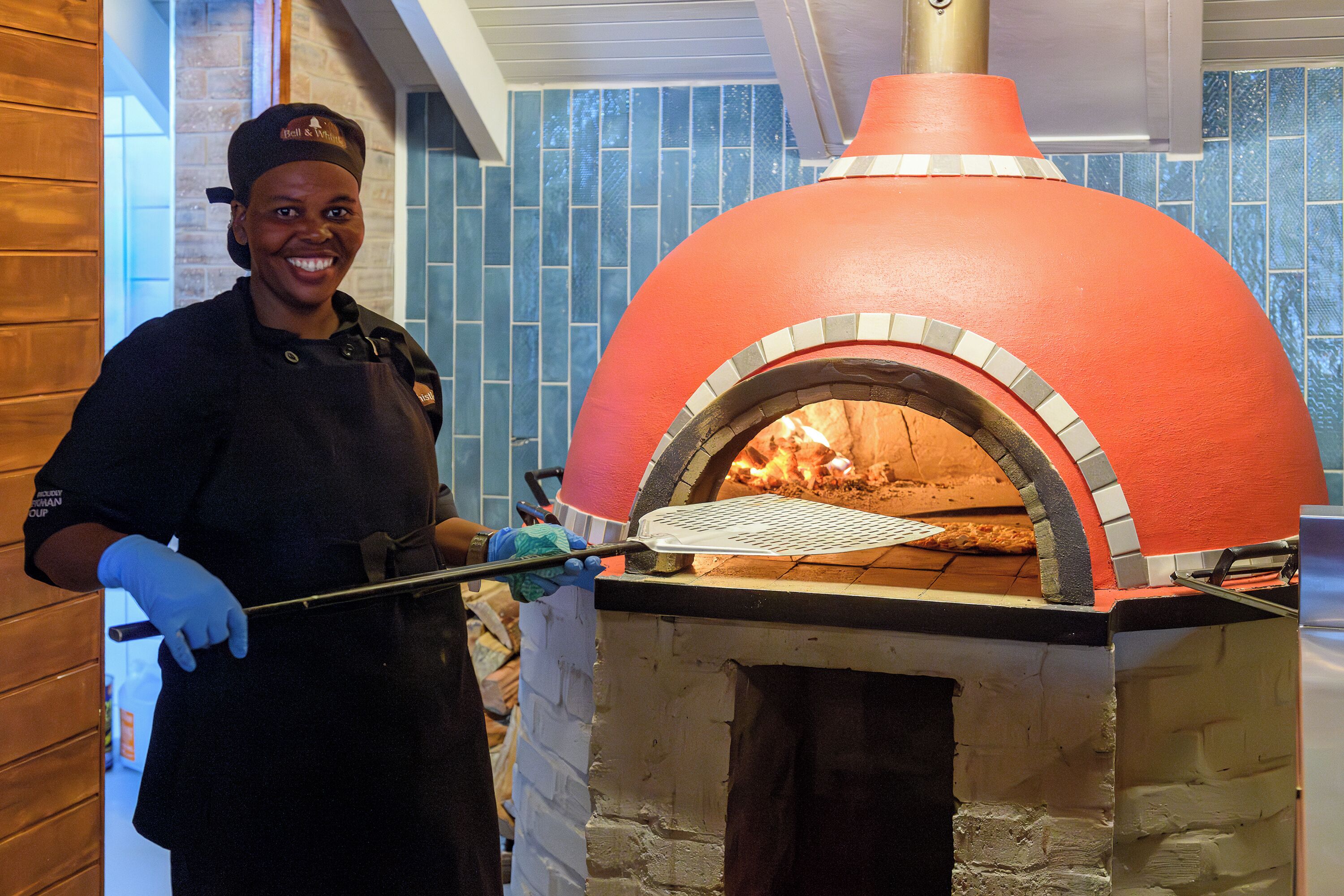 Una persona operando un horno de pizza de ladrillo.