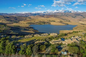 Un paisaje rural con un lago, casas y montañas al fondo.