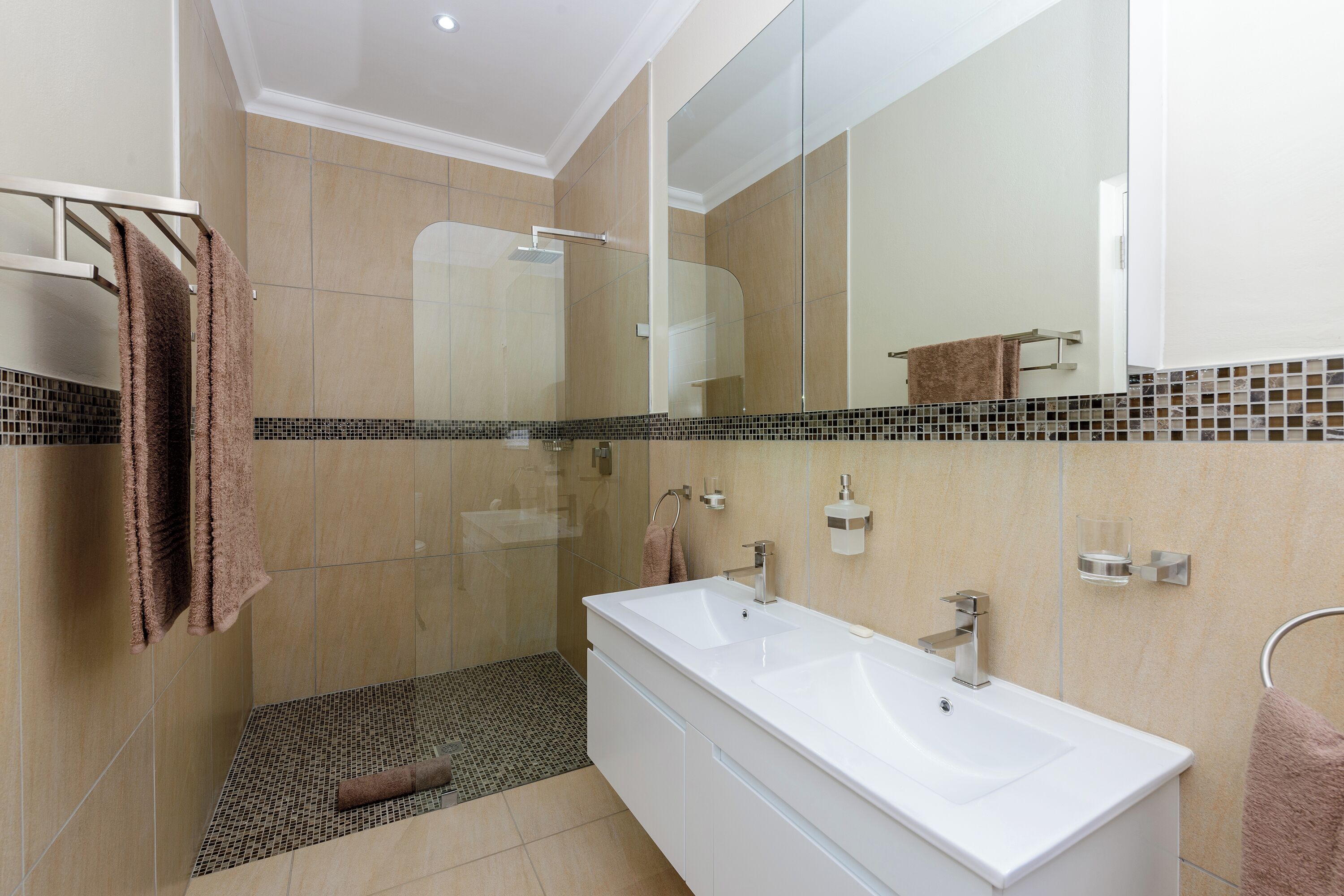 A modern bathroom with a large white sink, a glass shower enclosure, and a tiled floor.