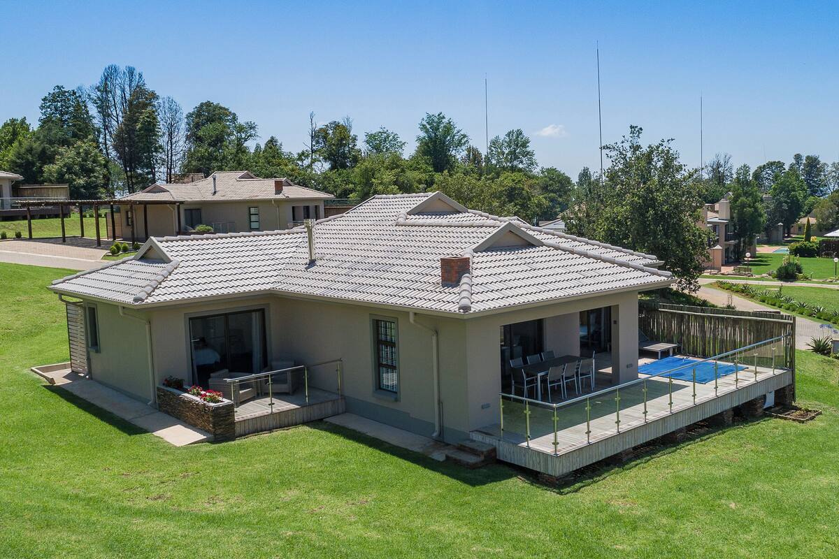 Une maison à deux étages dotée d’un patio couvert, d’une piscine et d’une pelouse bien entretenue.