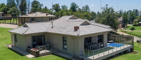 A two-story house with a covered patio, a swimming pool, and a well-maintained lawn.