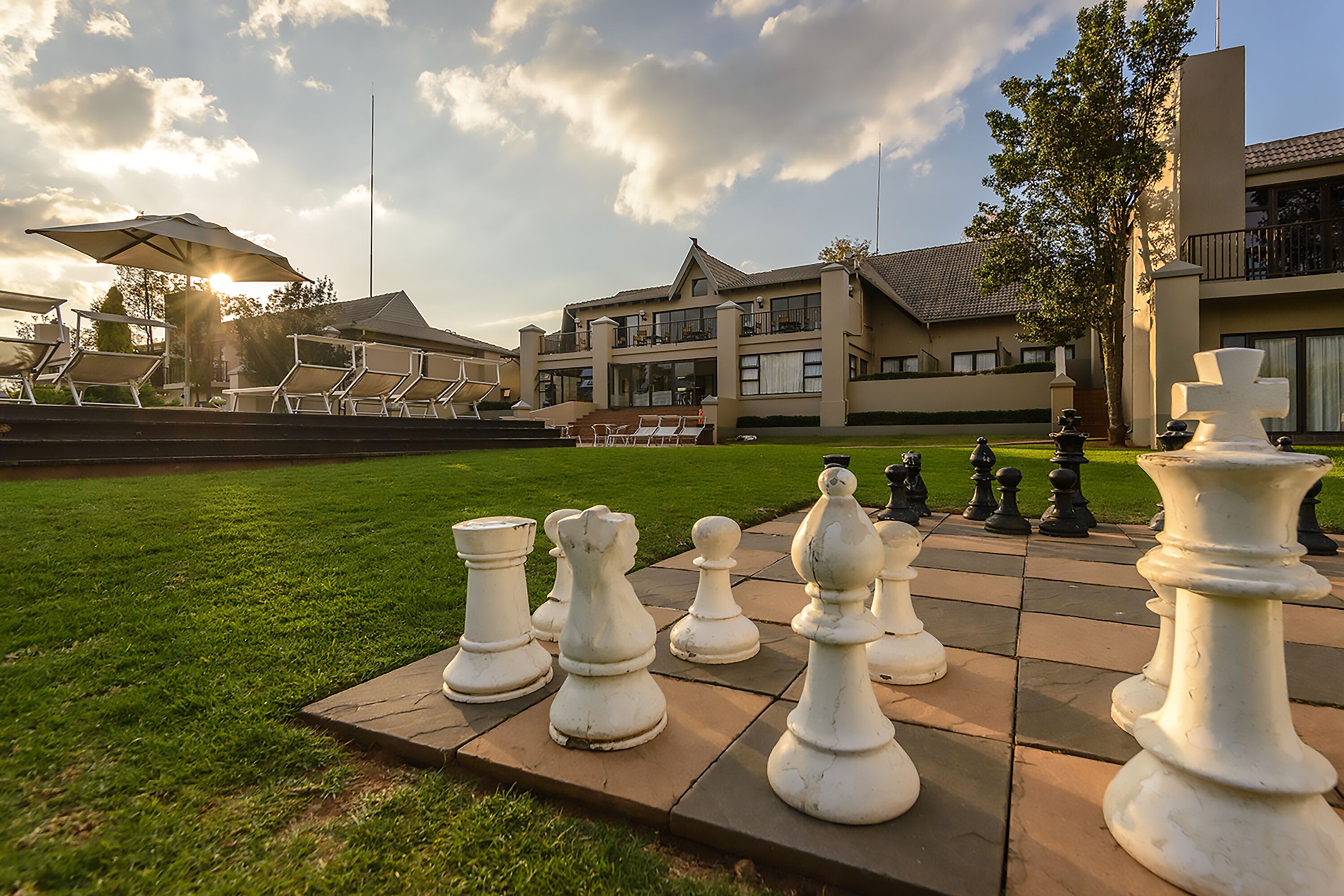 A chessboard set on a patio with a building in the background.