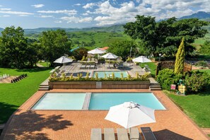 Una piscina al aire libre, sombrillas, sillones reclinables de piscina