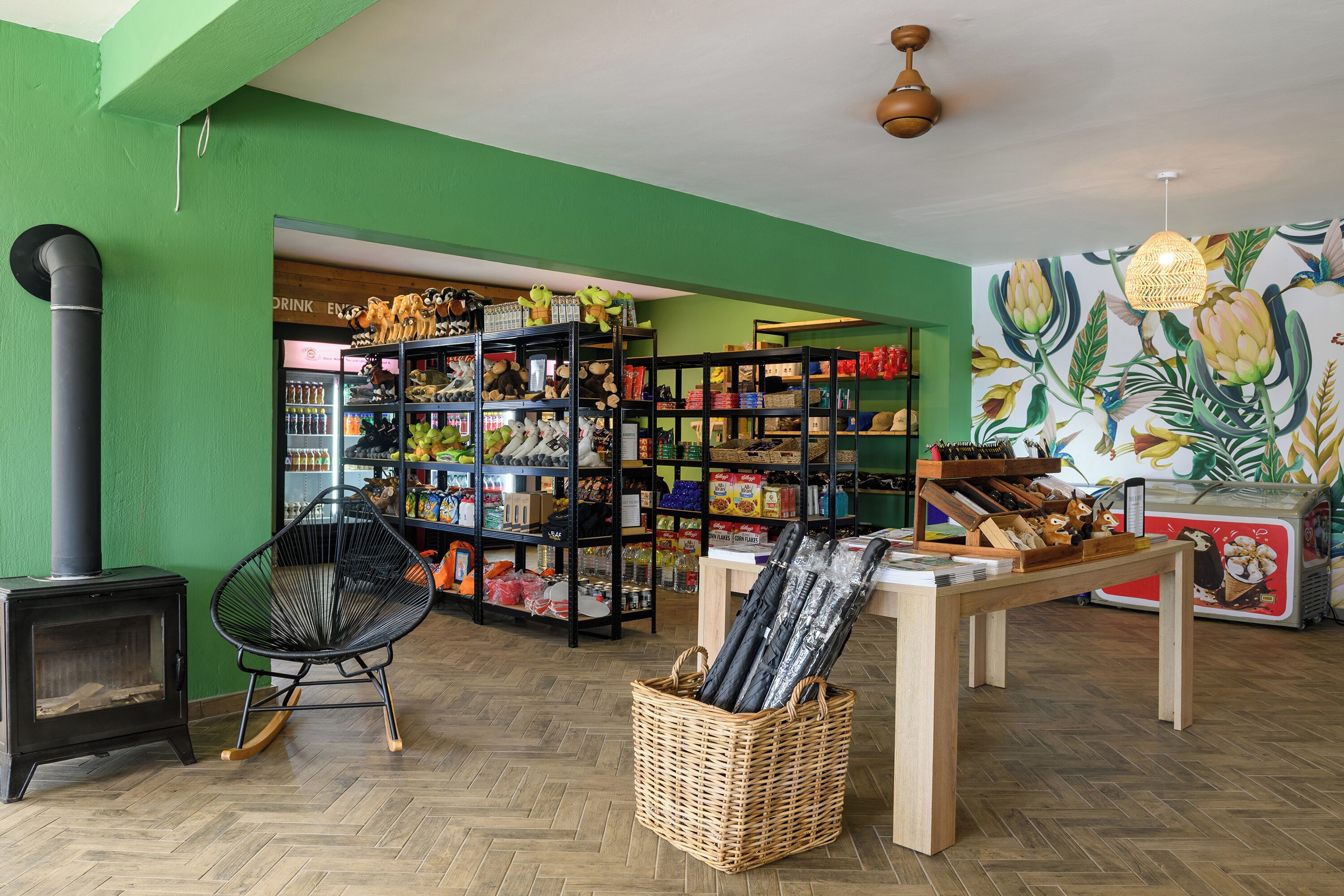 A room with a green wall, a black chair, a wooden table, and shelves filled with various items.