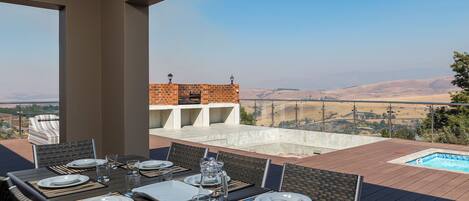 An outdoor dining area with a view of a pool and distant hills.