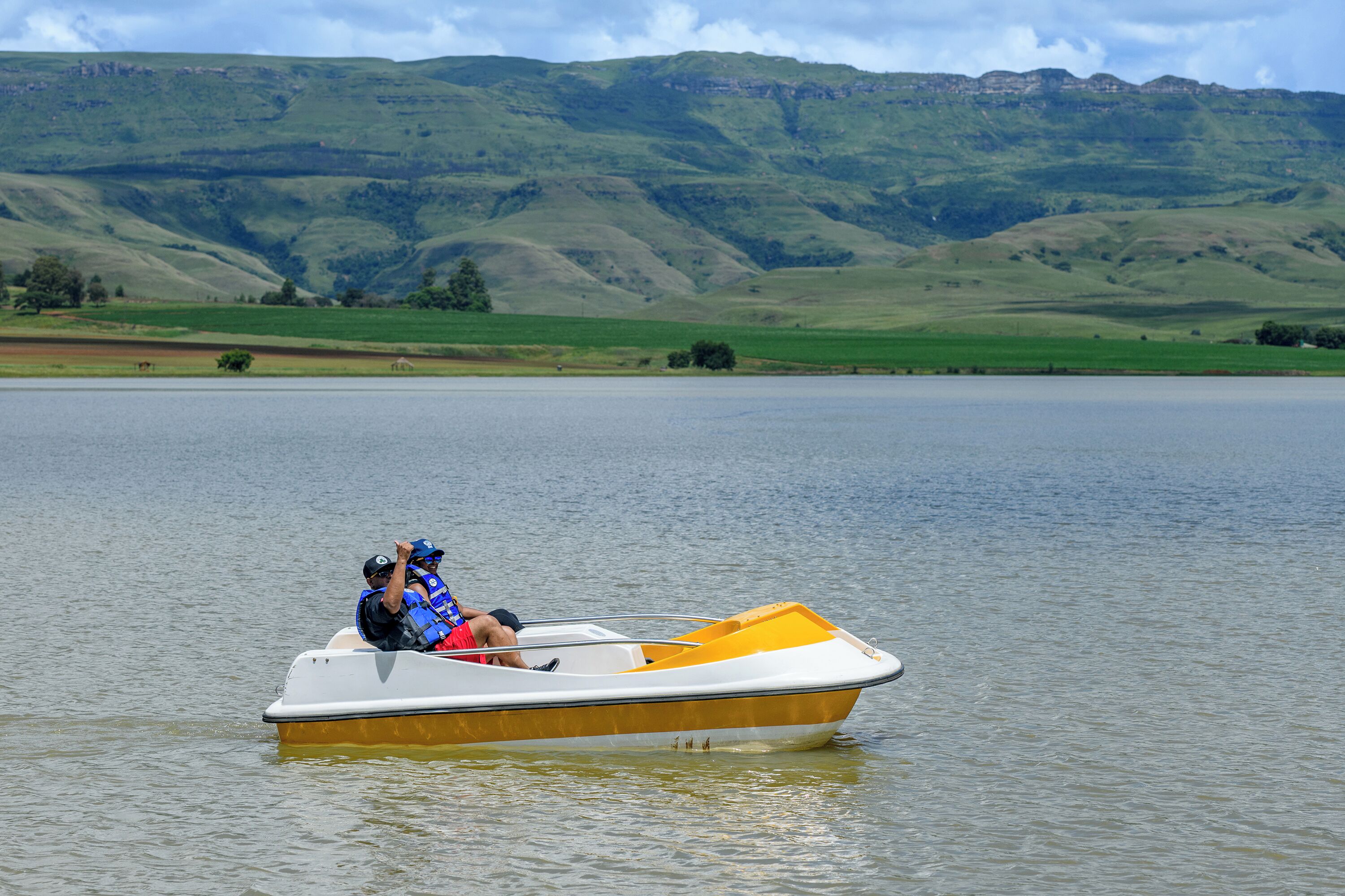 Una pequeña embarcación en un lago tranquilo con un paisaje montañoso al fondo.