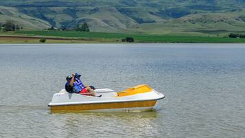 Una pequeña embarcación en un lago tranquilo con un paisaje montañoso al fondo.