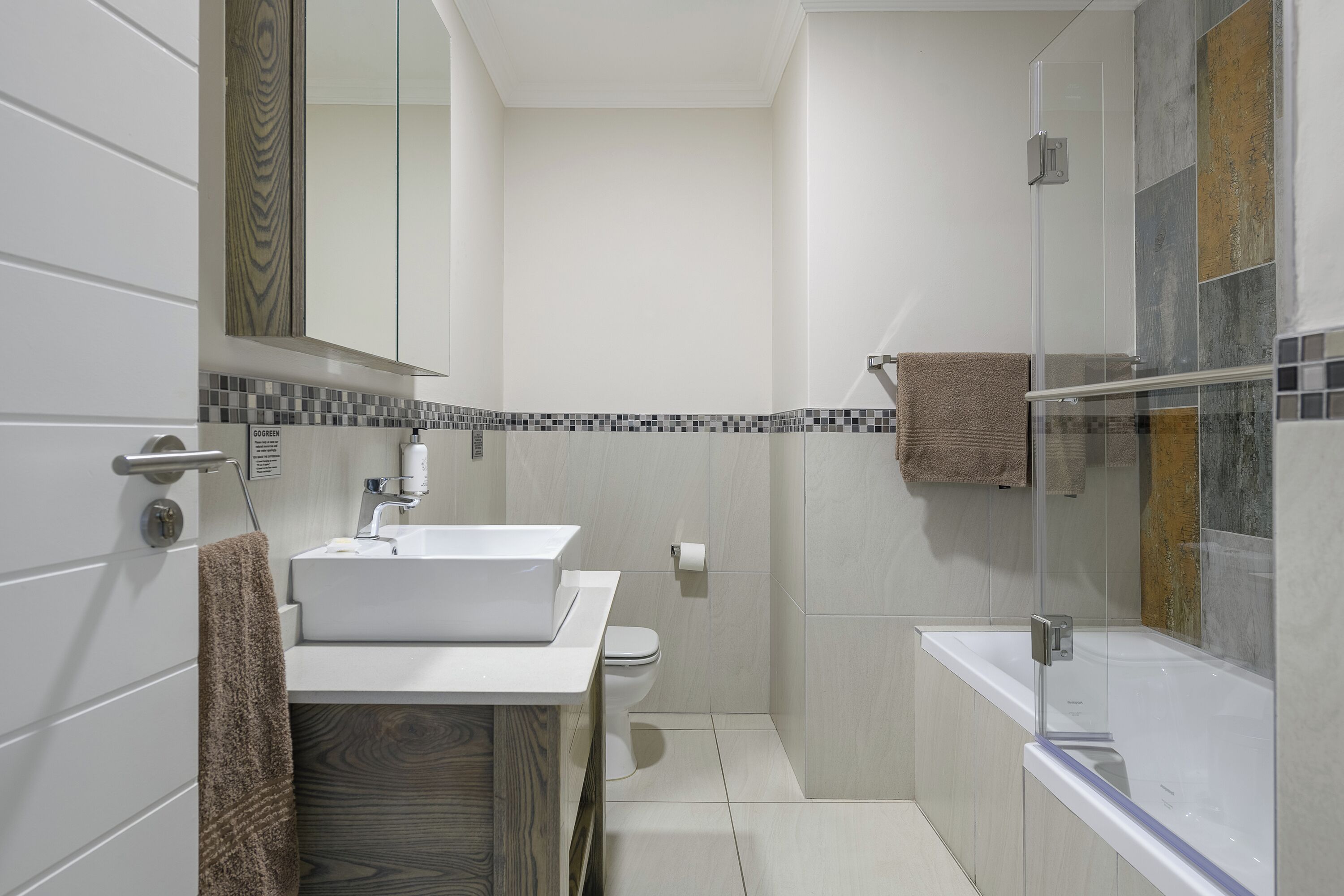 A modern bathroom with a white sink, toilet, and glass-enclosed shower.