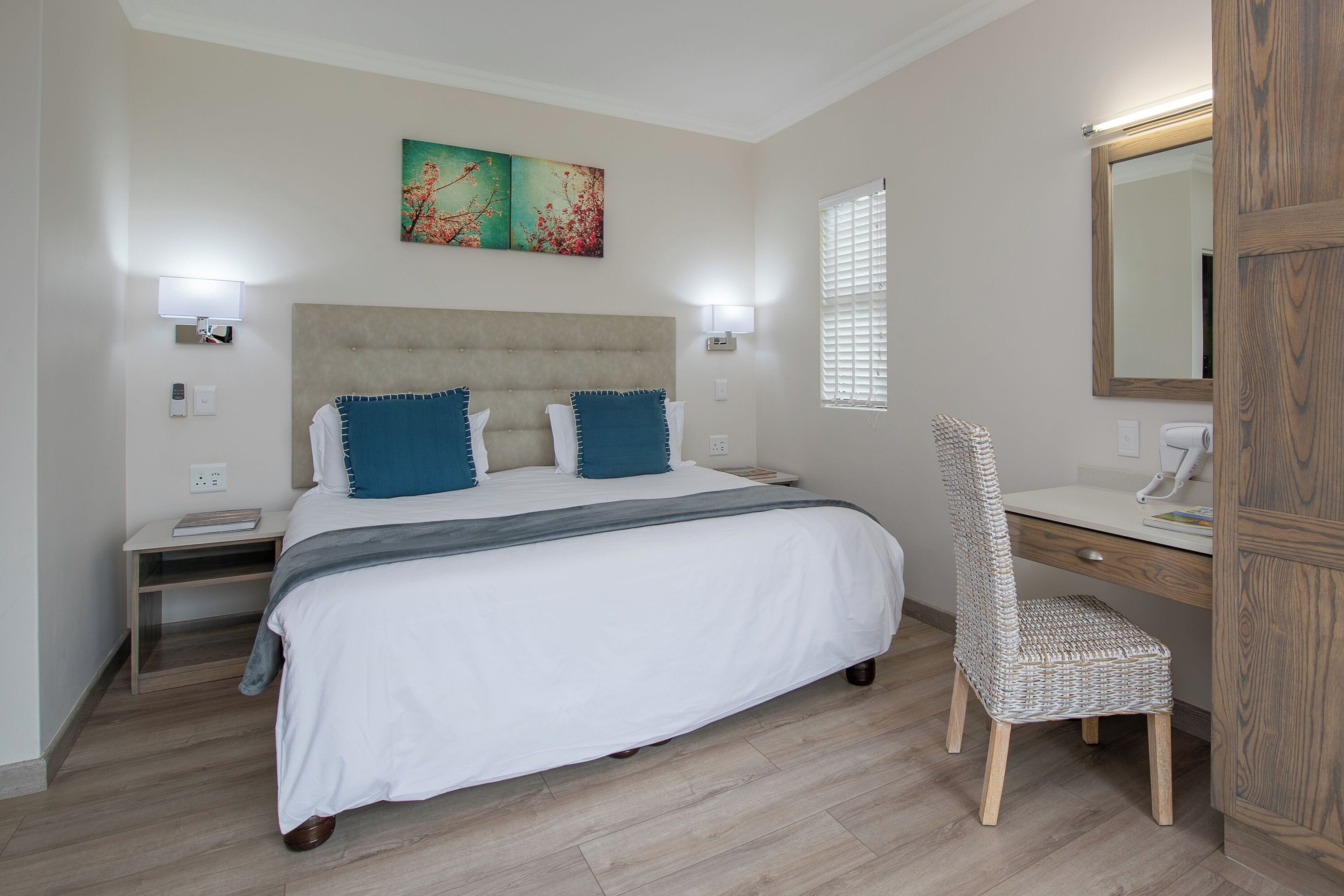 A bedroom with a bed, bedside tables, a desk, and a chair.