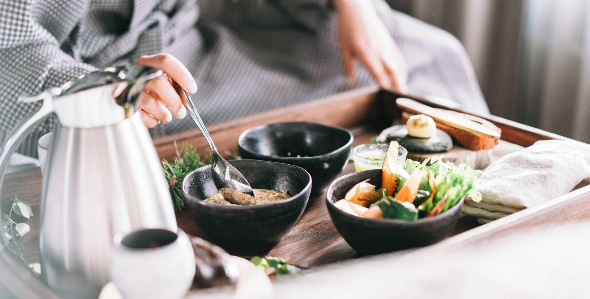 A tray with bowls of food, a kettle, and a cup.