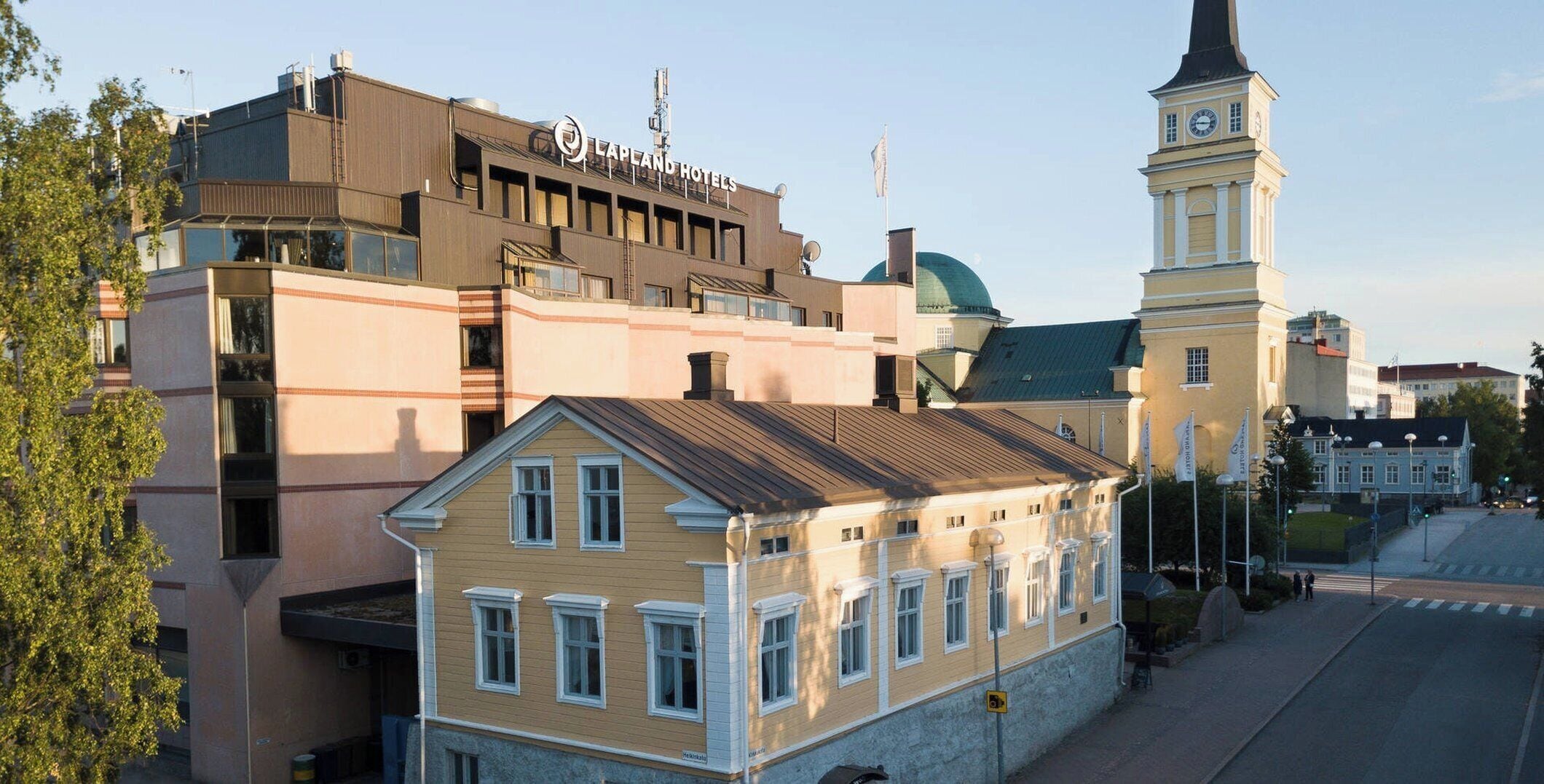 A building with a flat roof, a clock tower, and a sign for 'LaPland Hotels'.