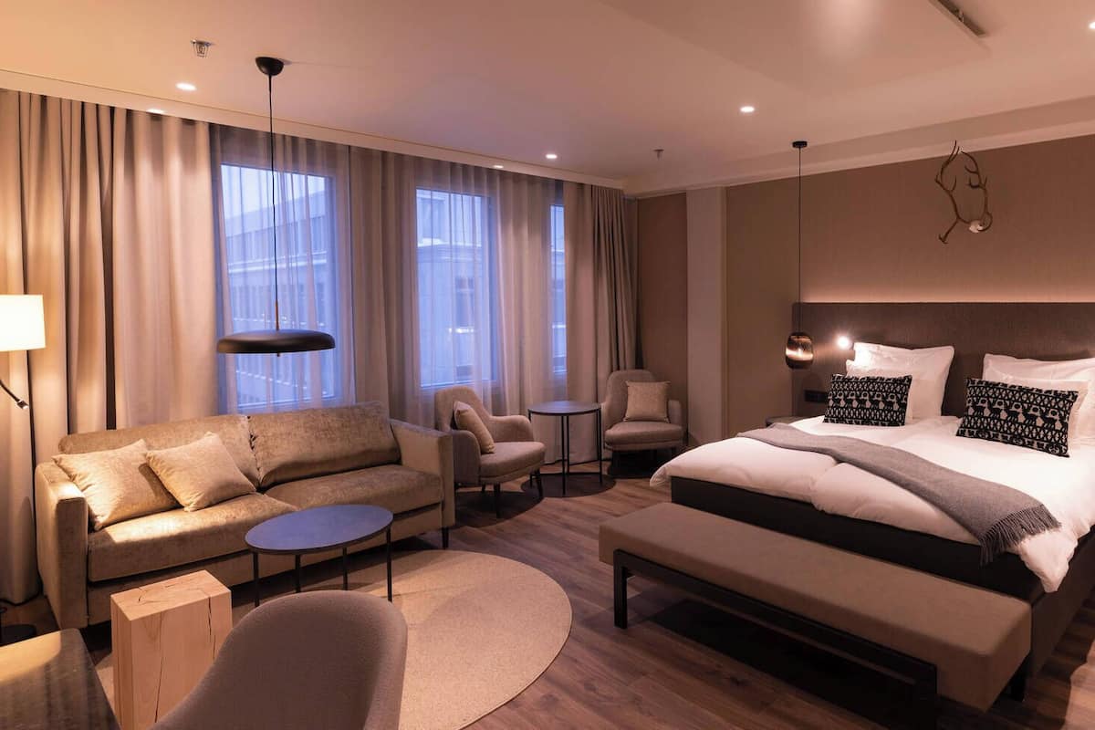 Une chambre d’hôtel moderne avec un grand lit, un canapé, une petite table et une chaise.