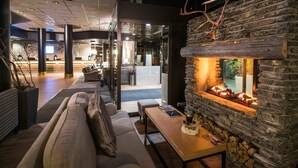 Un moderno vestíbulo con chimenea de piedra, un sofá y una mesa de madera.
