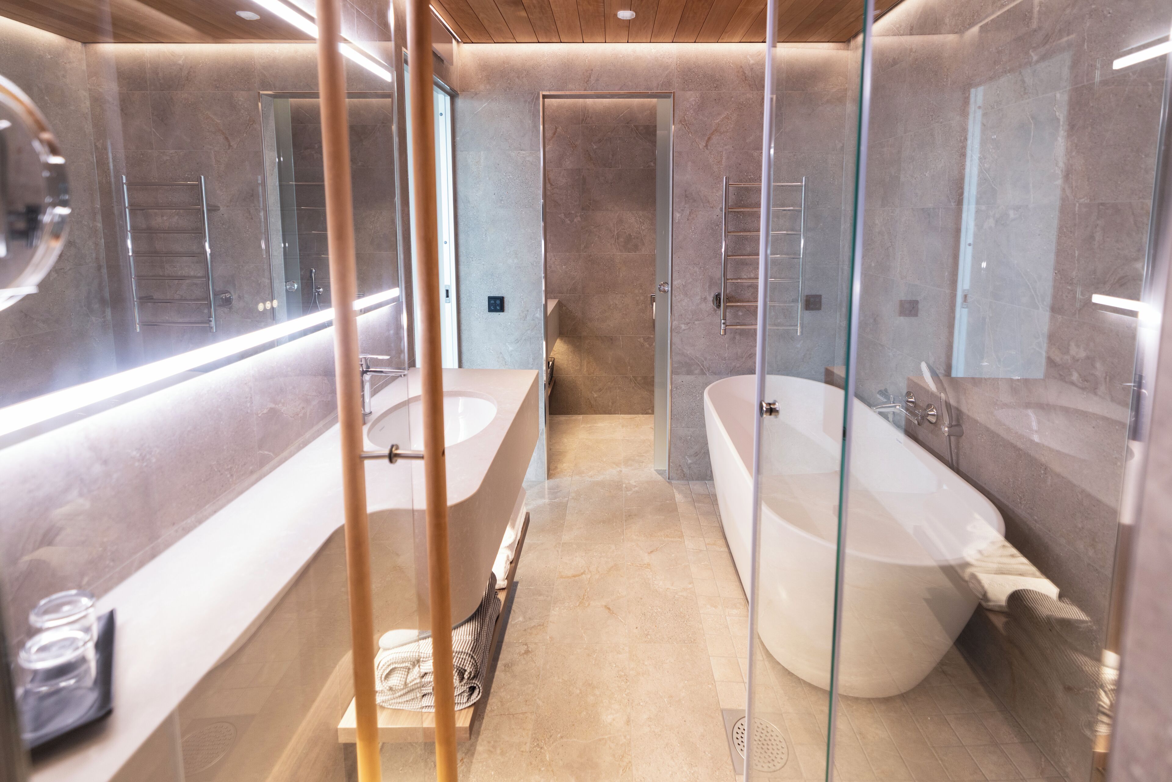 A modern bathroom with a large bathtub, a separate shower area, and a glass-enclosed vanity.