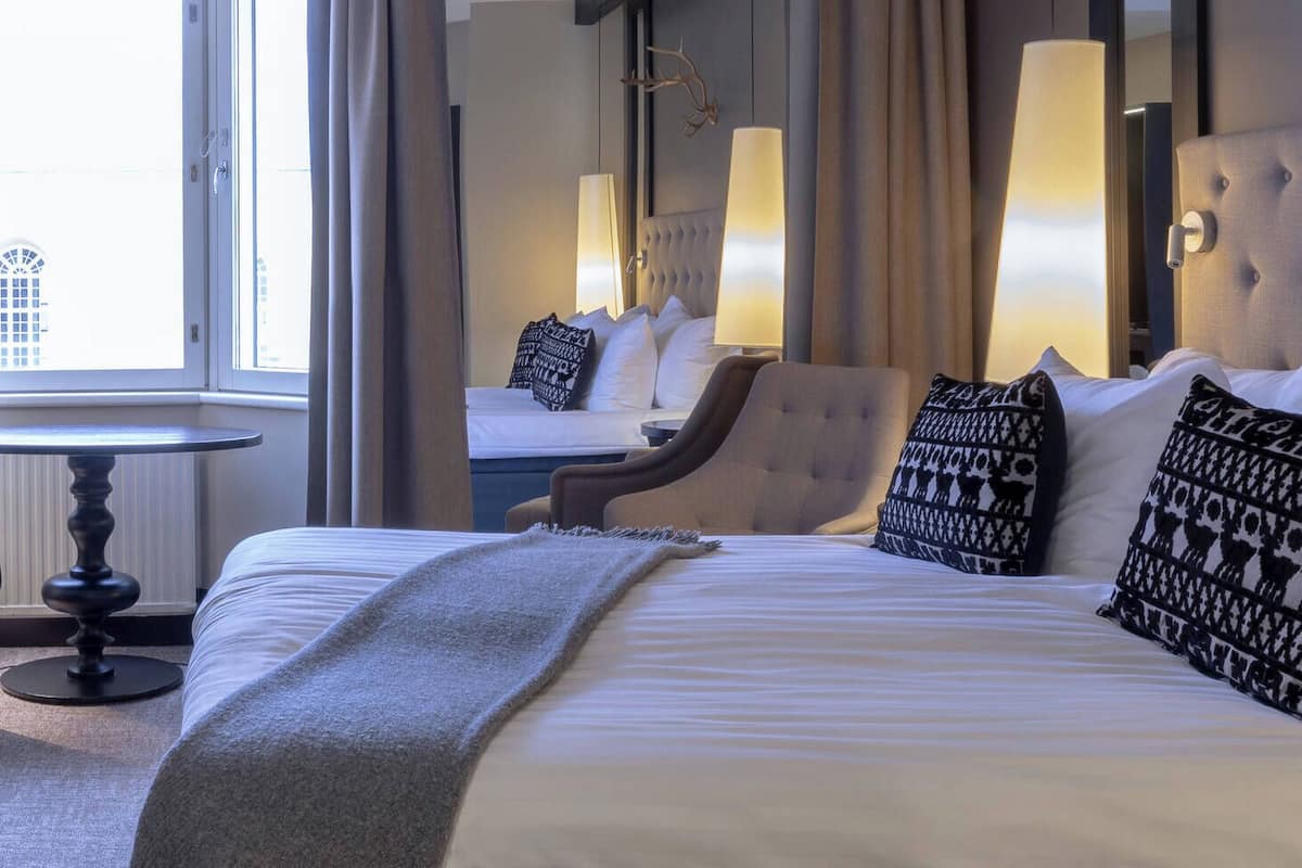 Une chambre d’hôtel avec un grand lit, une chaise, une table et un miroir.