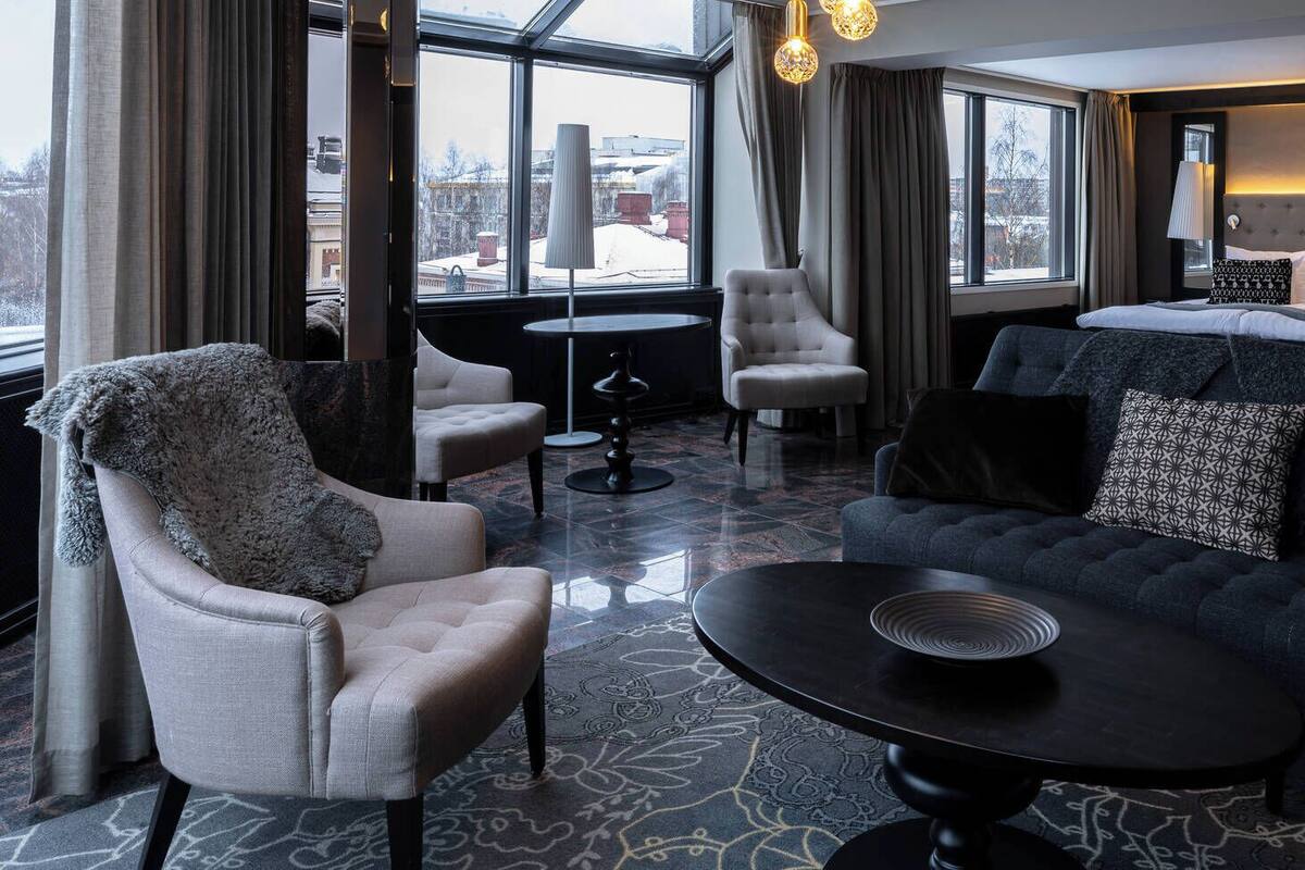 Une chambre d’hôtel moderne avec un canapé, un fauteuil et une table ronde.