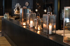 Eine Bar mit Glaskolben, die Kerzen enthalten, einer Felldekoration und einer Uhr an der Wand.