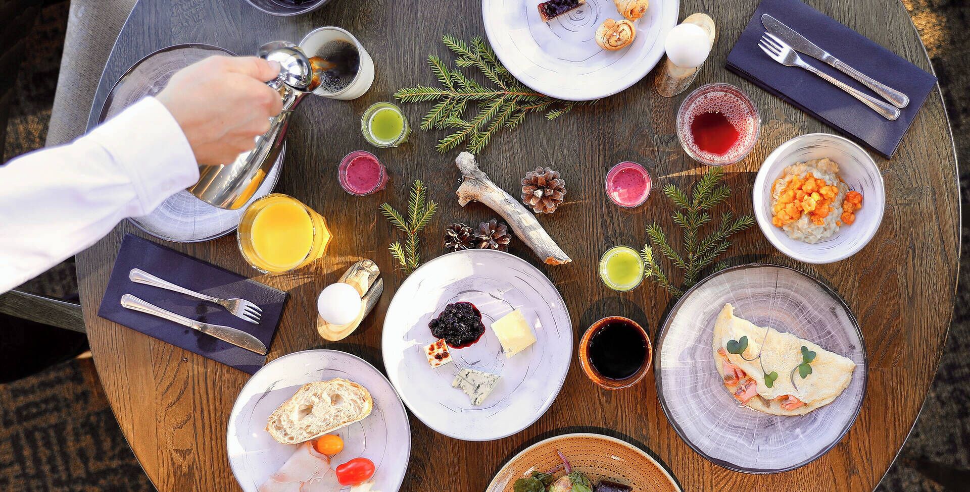 A breakfast setting with various dishes, utensils, and a coffee cup on a wooden table.