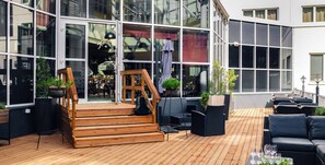 A wooden deck with outdoor seating, a staircase leading to a glass door entrance, and potted plants. - Lapland Hotels Tampere (Tampere)