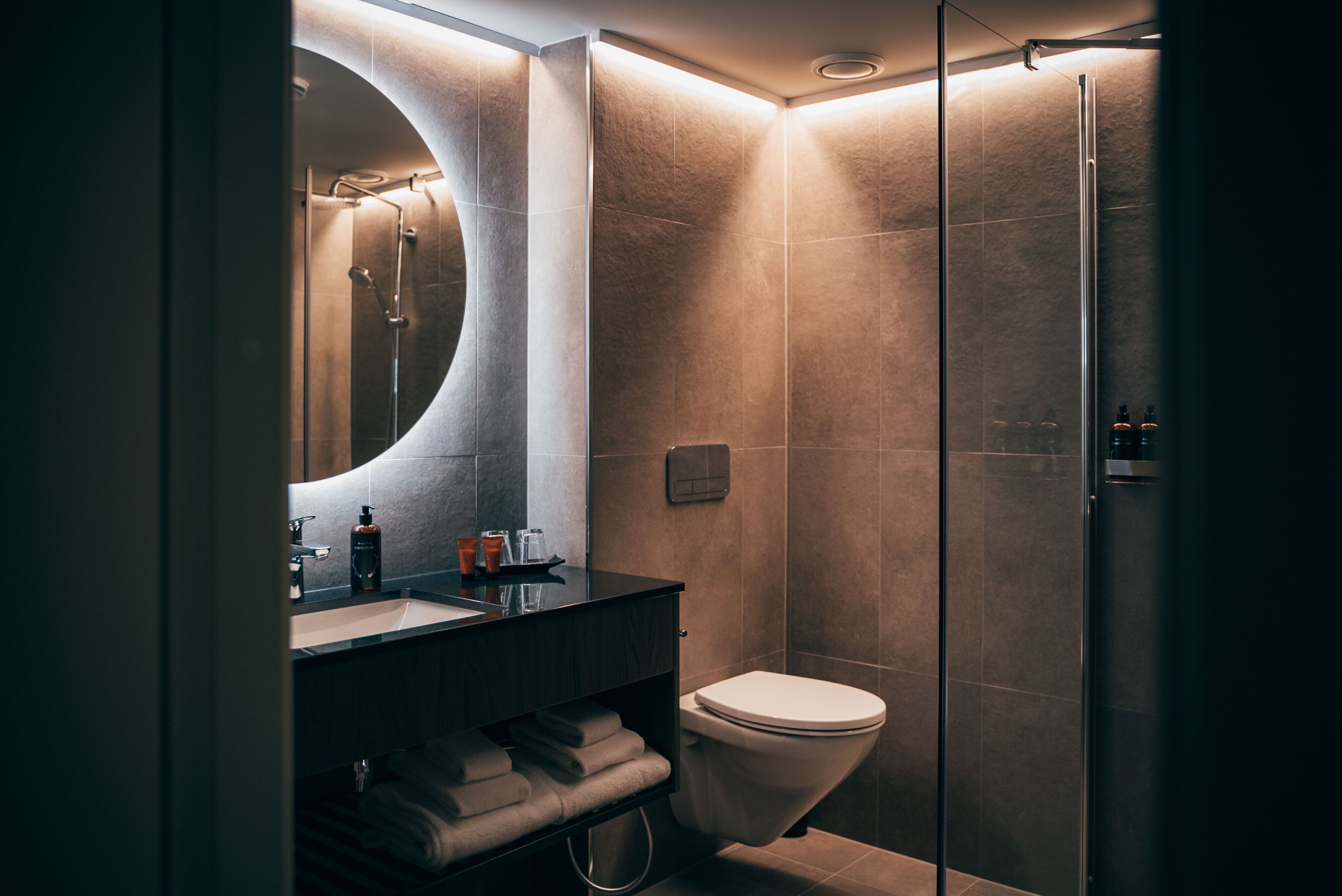 Un baño moderno con un espejo curvo, un lavabo y un inodoro.