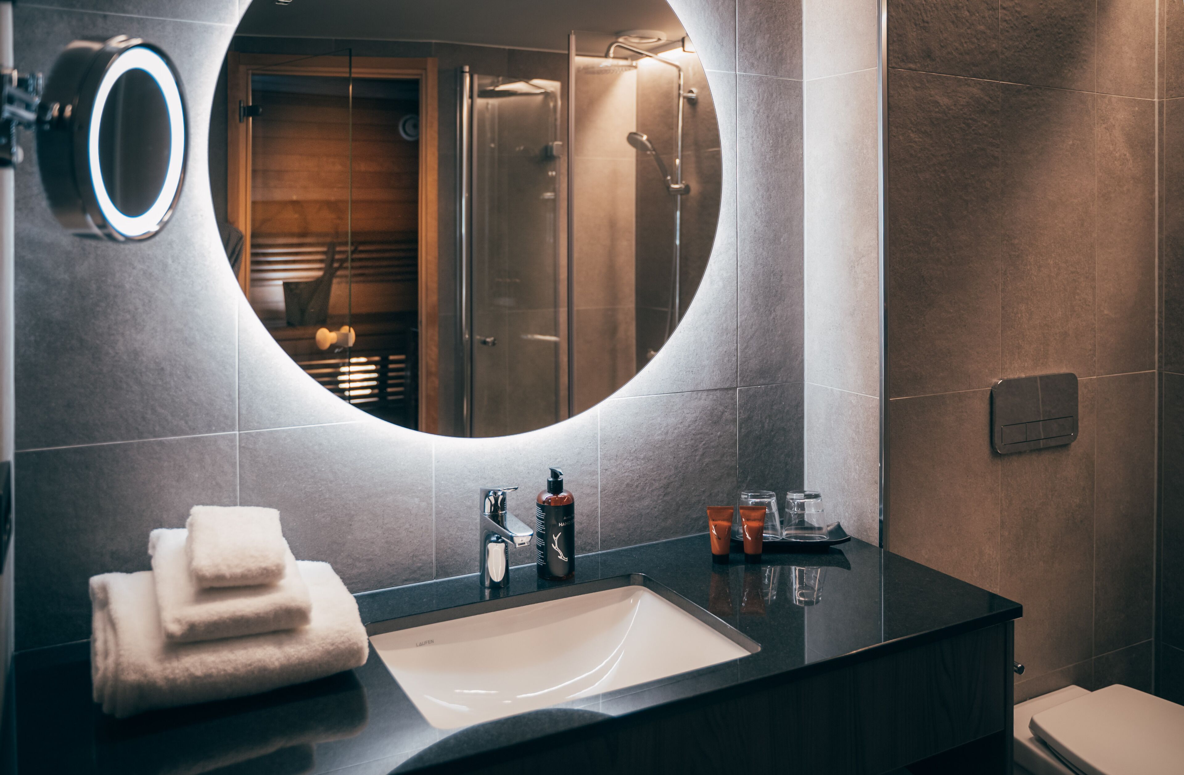 A modern bathroom with a large mirror, a sink, and a shower.