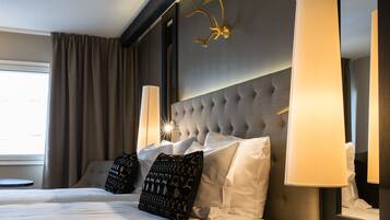 Habitación de hotel con una cama grande, un cabecero capitonado y dos lámparas fijadas a la pared.