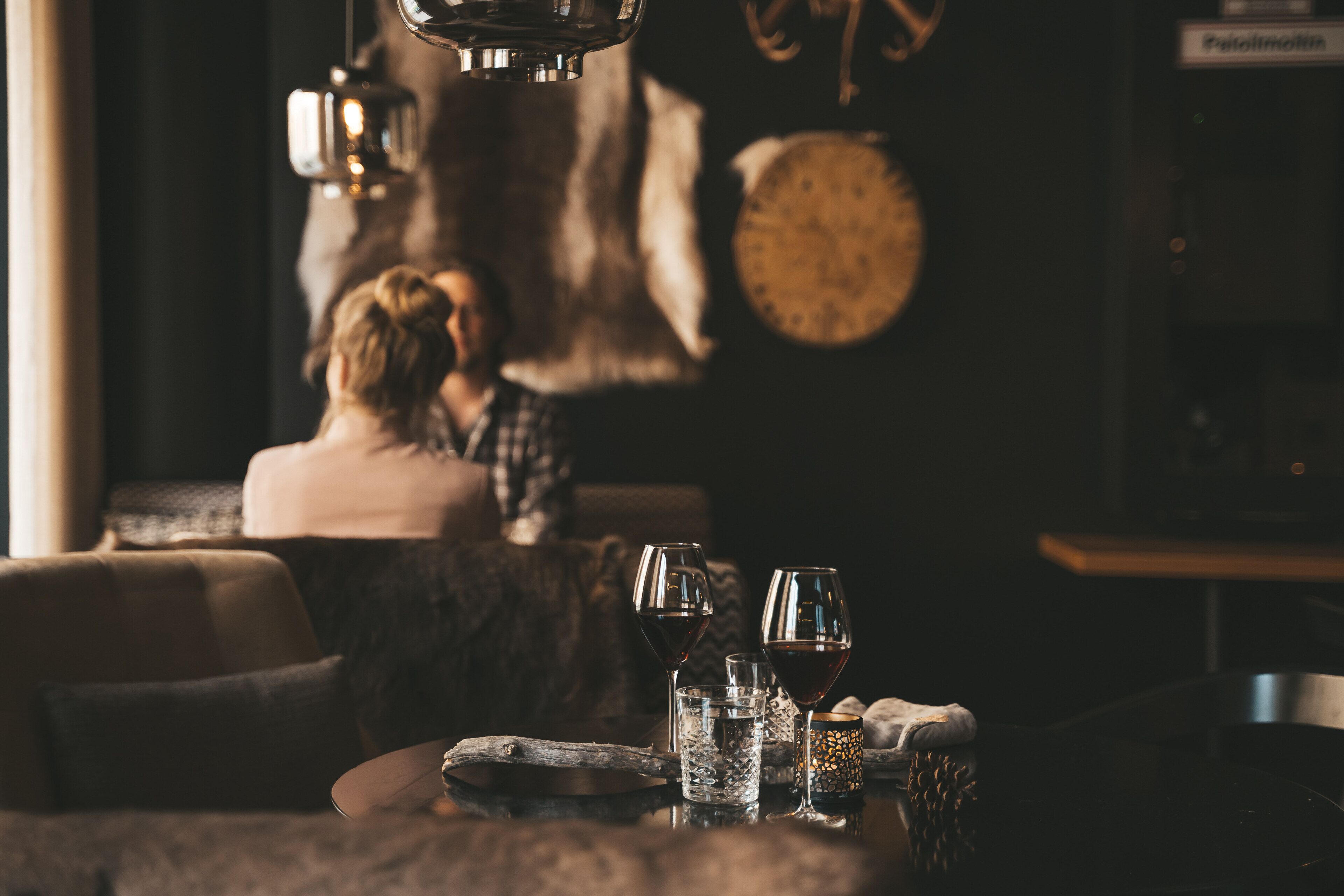 A cozy dining area with a table set for two, featuring wine glasses and a rustic wooden table.