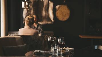 A cozy dining area with a table set for two, featuring wine glasses and a rustic wooden table.