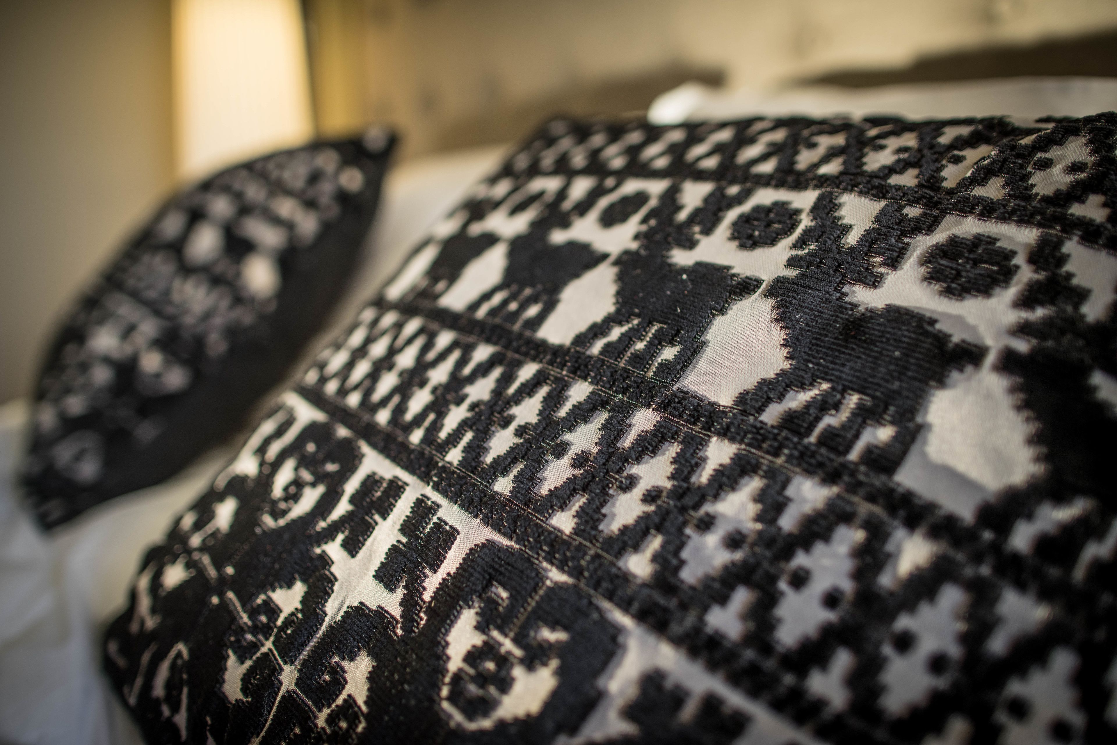 A close-up of a patterned fabric, likely a pillow or cushion, with a geometric design.